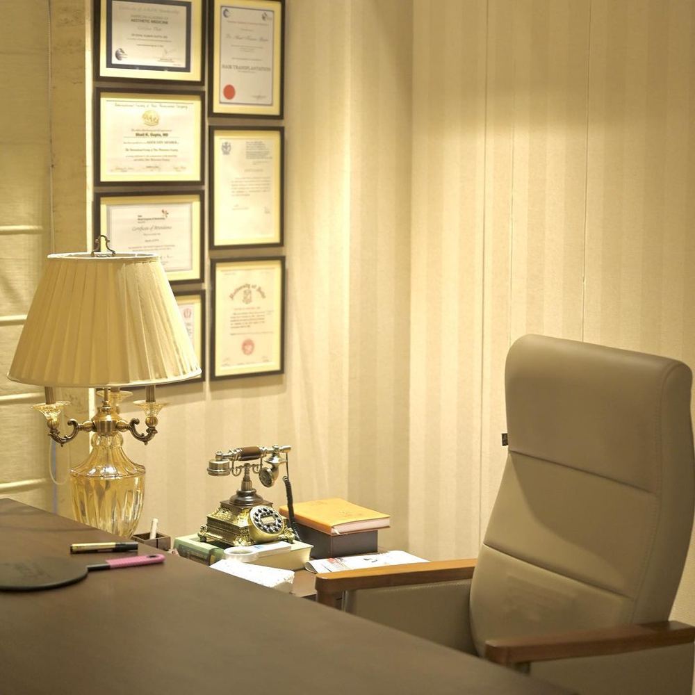 Consultation desk with a brass table lamp and framed certificates