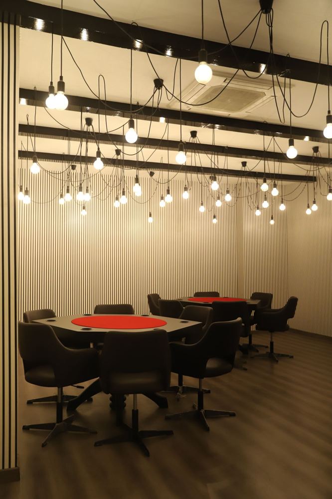 Cards room with retro bulb pendants and red-topped game tables